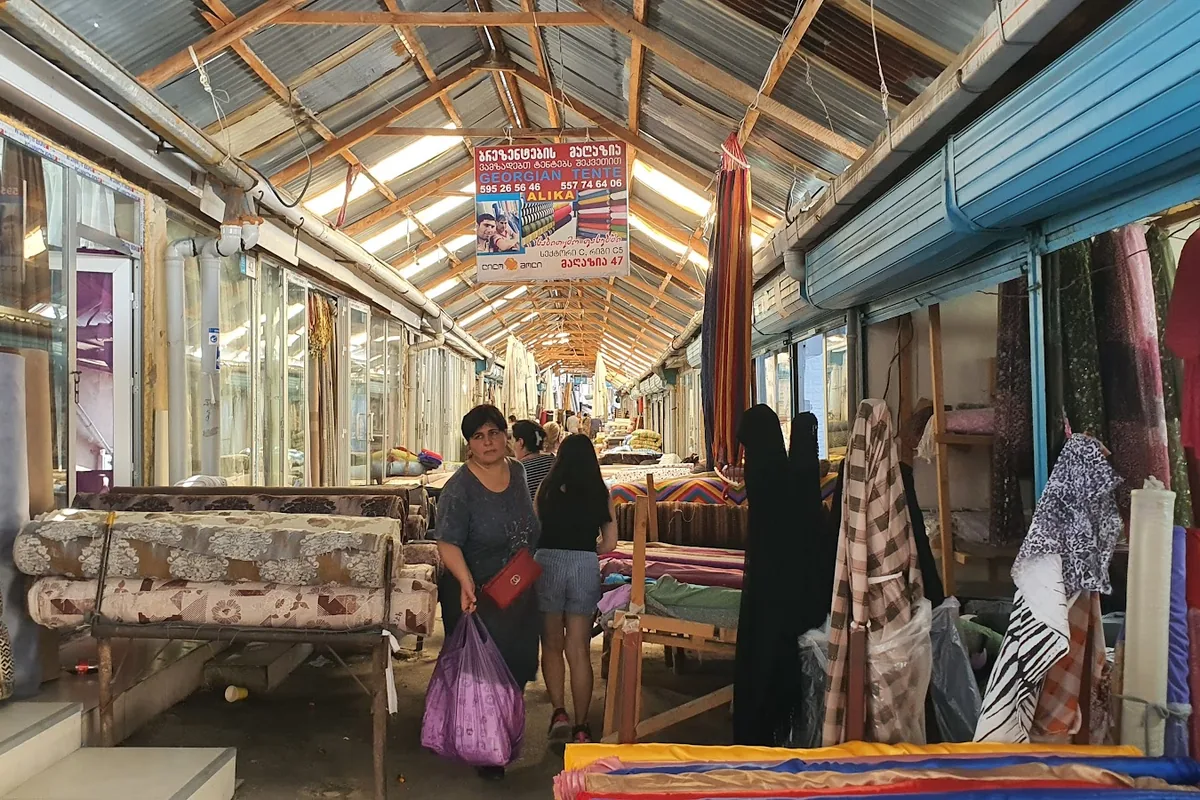 Covered aisle lined with fabric and curtain shops at Lilo Market