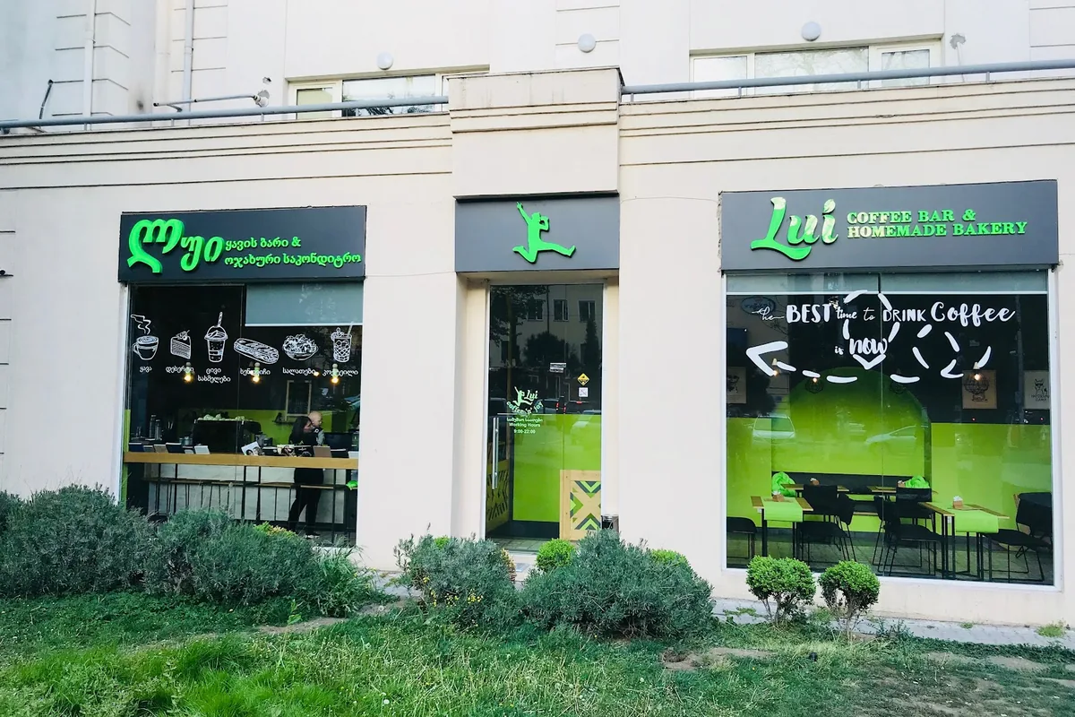 Green-lit shopfront of Lui Coffee Bar and Homemade Bakery on Chavchavadze Avenue