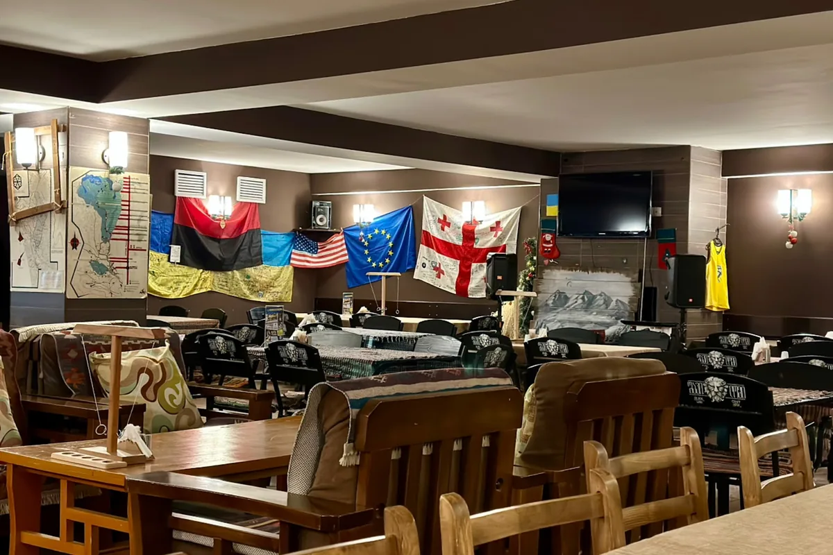 Wooden tables and benches under flags from around the world in the dining room at Magi Style in Gudauri