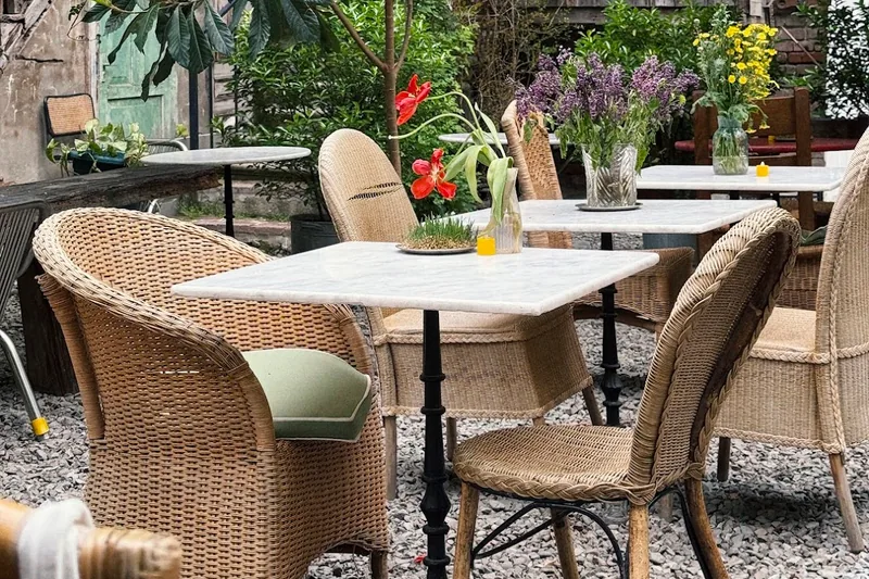 Gravel courtyard patio with wicker chairs and marble tables at Mova Maisi