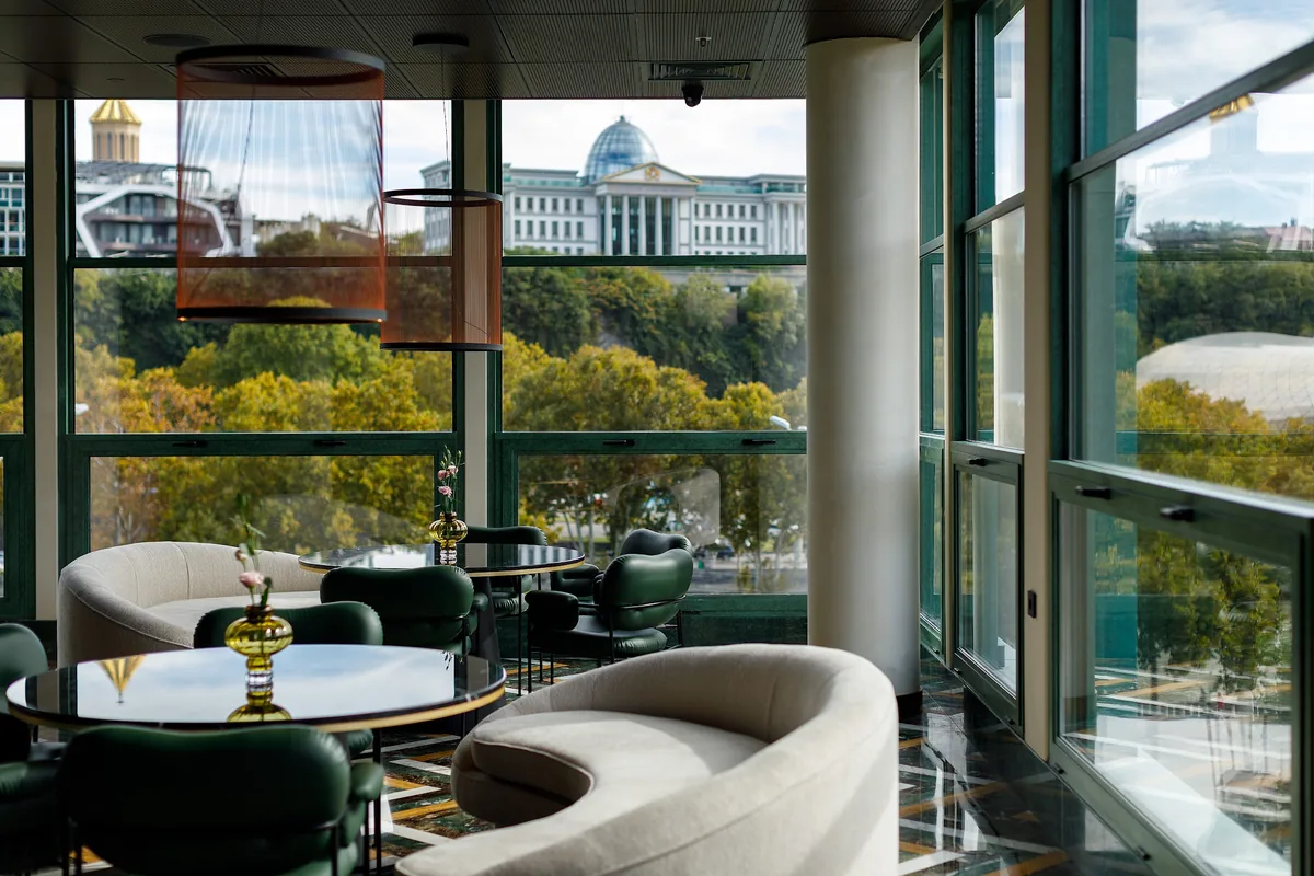Mozaiko, the Ambassadori's restaurant, with green chairs and tall windows looking across the river to the Presidential Palace