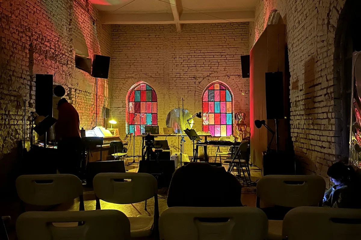 The brick event room with stained-glass arched windows and DJ gear at Mutant Radio