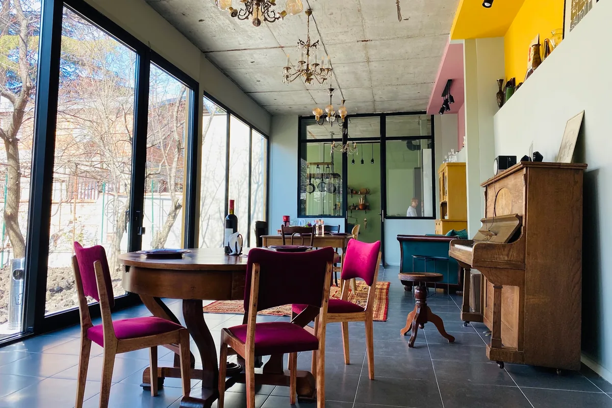Dining space with floor-to-ceiling windows and piano at Nana's Kitchen Cooking Classes