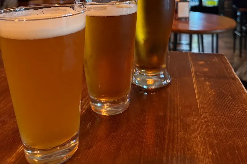 Three glasses of craft beer on a wooden table at Number 8 - Craft Beer Club
