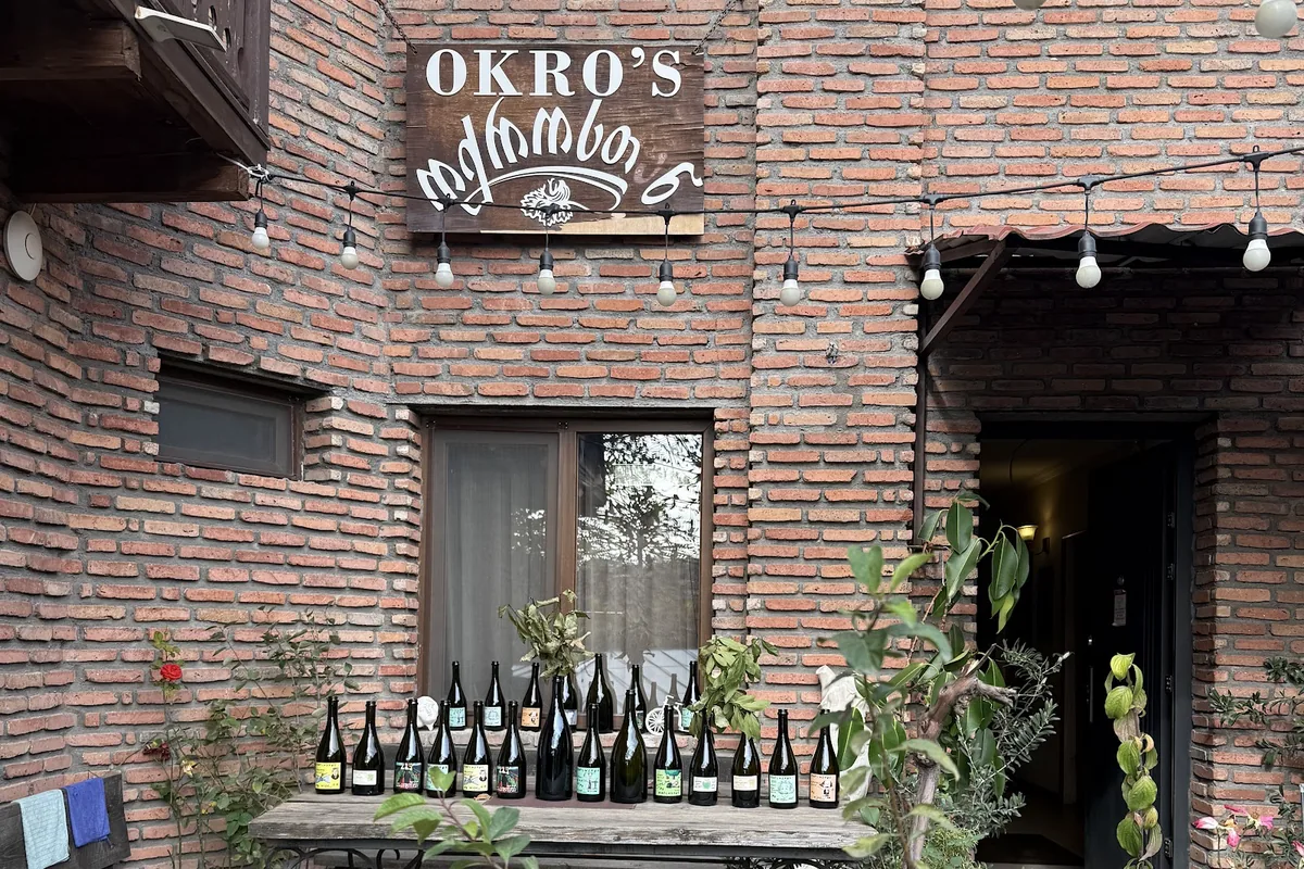 The brick courtyard with its sign and a table of wine bottles at Okro's Wines in Sighnaghi