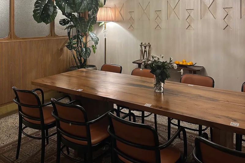 Wooden dining tables and chairs beneath a tiered chandelier at ORO Marjanishvili