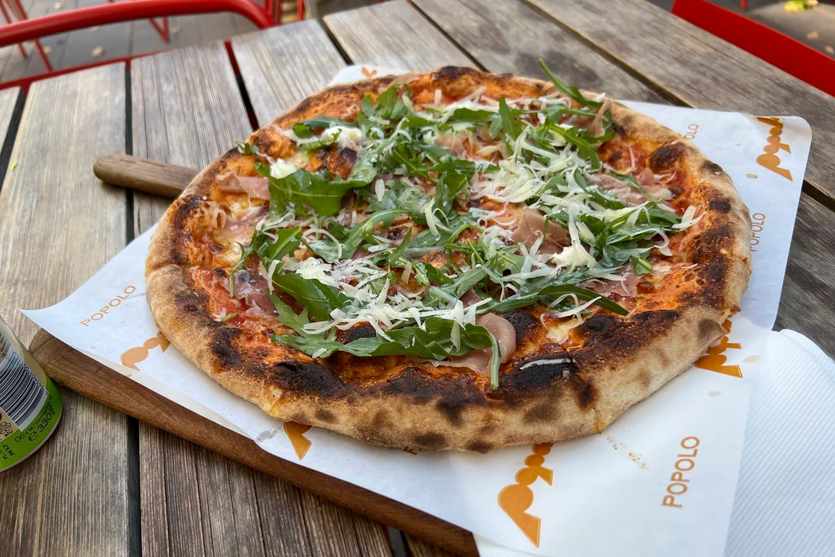 Wood-fired pizza topped with prosciutto, arugula and parmesan at Popolo