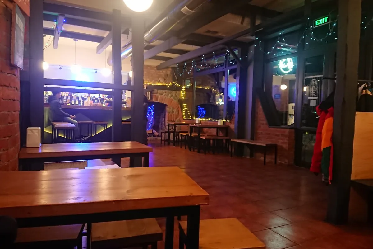 Wooden tables, brick walls and fairy lights around the lit bar counter at Powder Bar in Gudauri