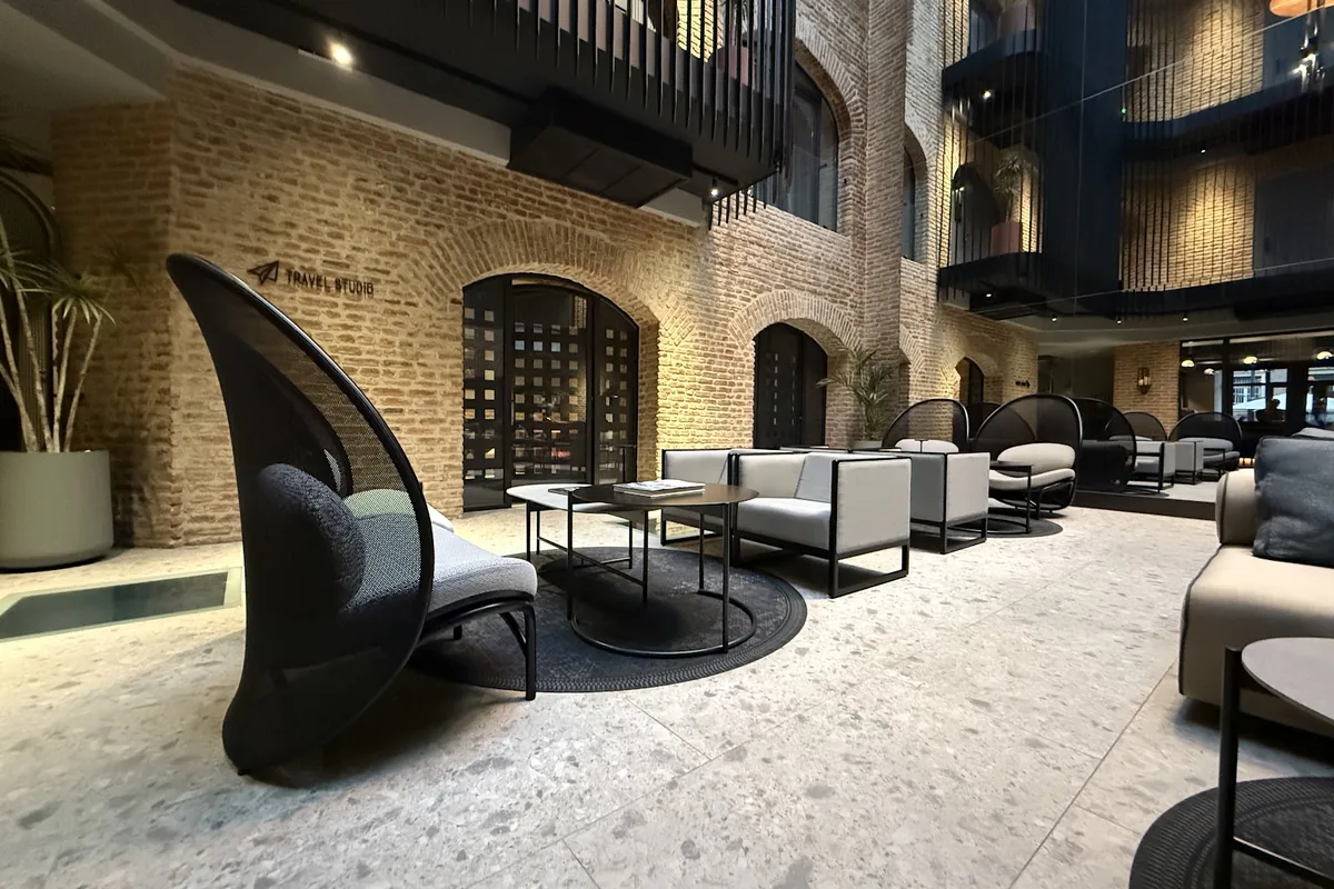 Brick-walled atrium lounge with arched doorways and black balconies at Qarvasla Hotel