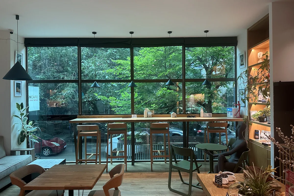 Window bar with high stools and pendant lamps looking onto a tree-lined street at RedMan Cafe