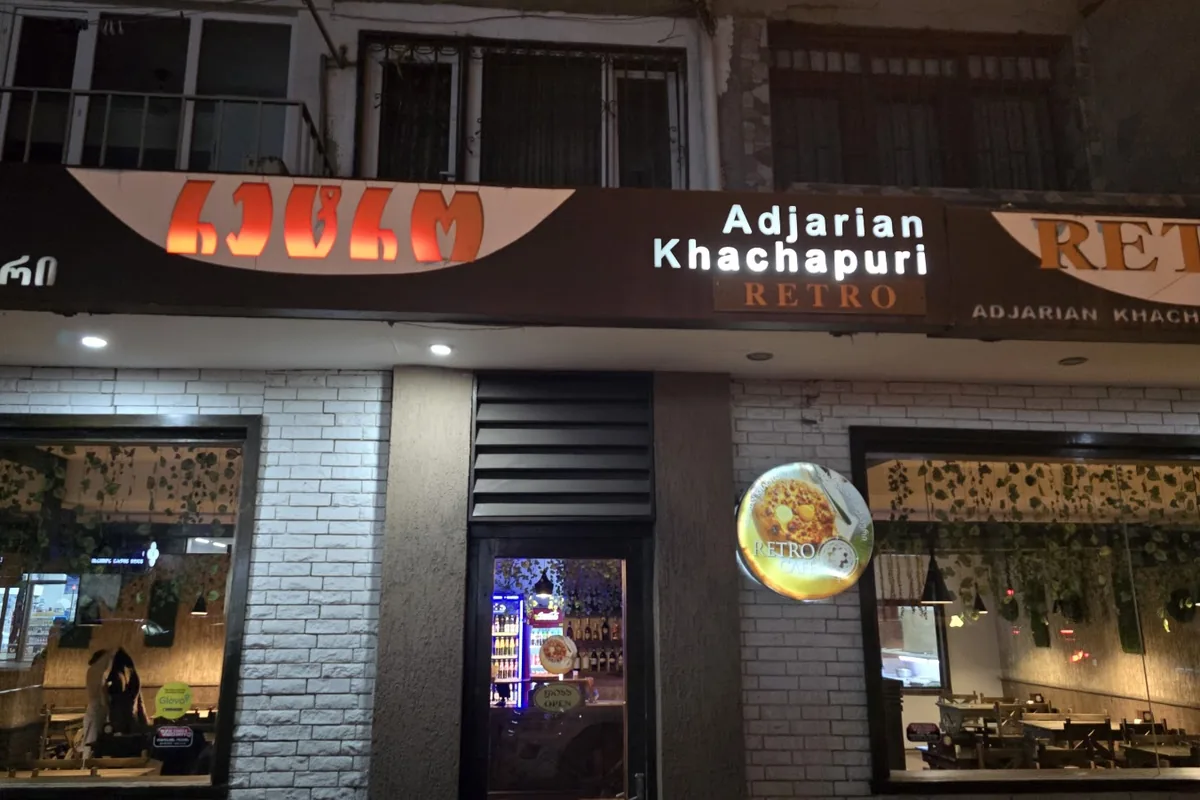 The lit Retro Adjarian Khachapuri signs over the white brick front and windows of Retro in Saburtalo