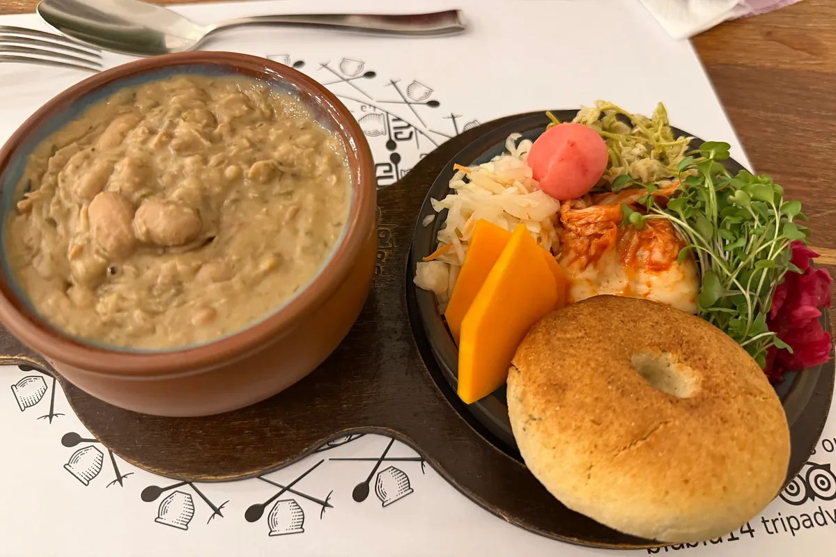Lobio in a clay pot served with mchadi and a plate of pickles at Salobie Bia