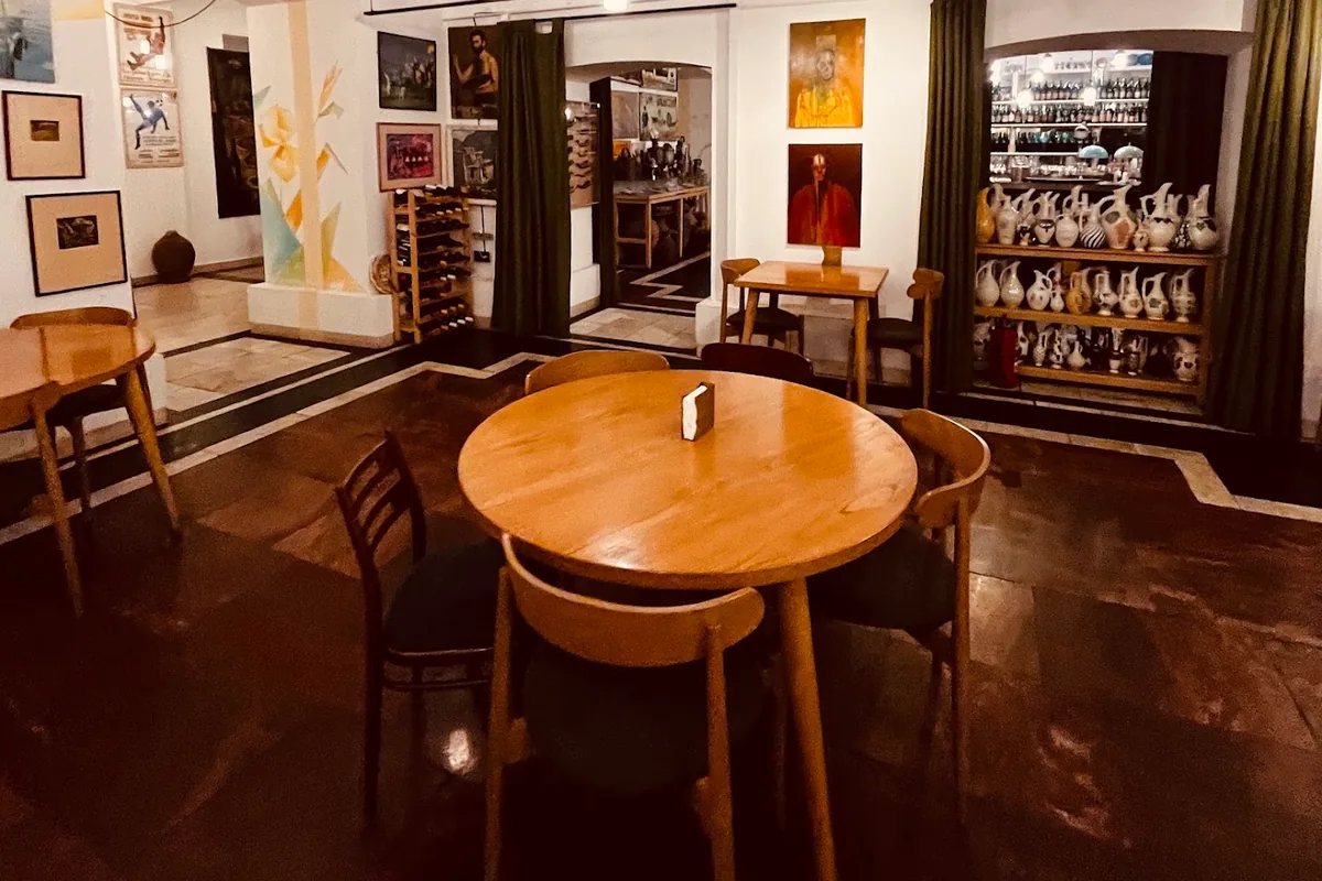 Round wooden tables, paintings and shelves of ceramic jugs in the dining room at Salobie Bia