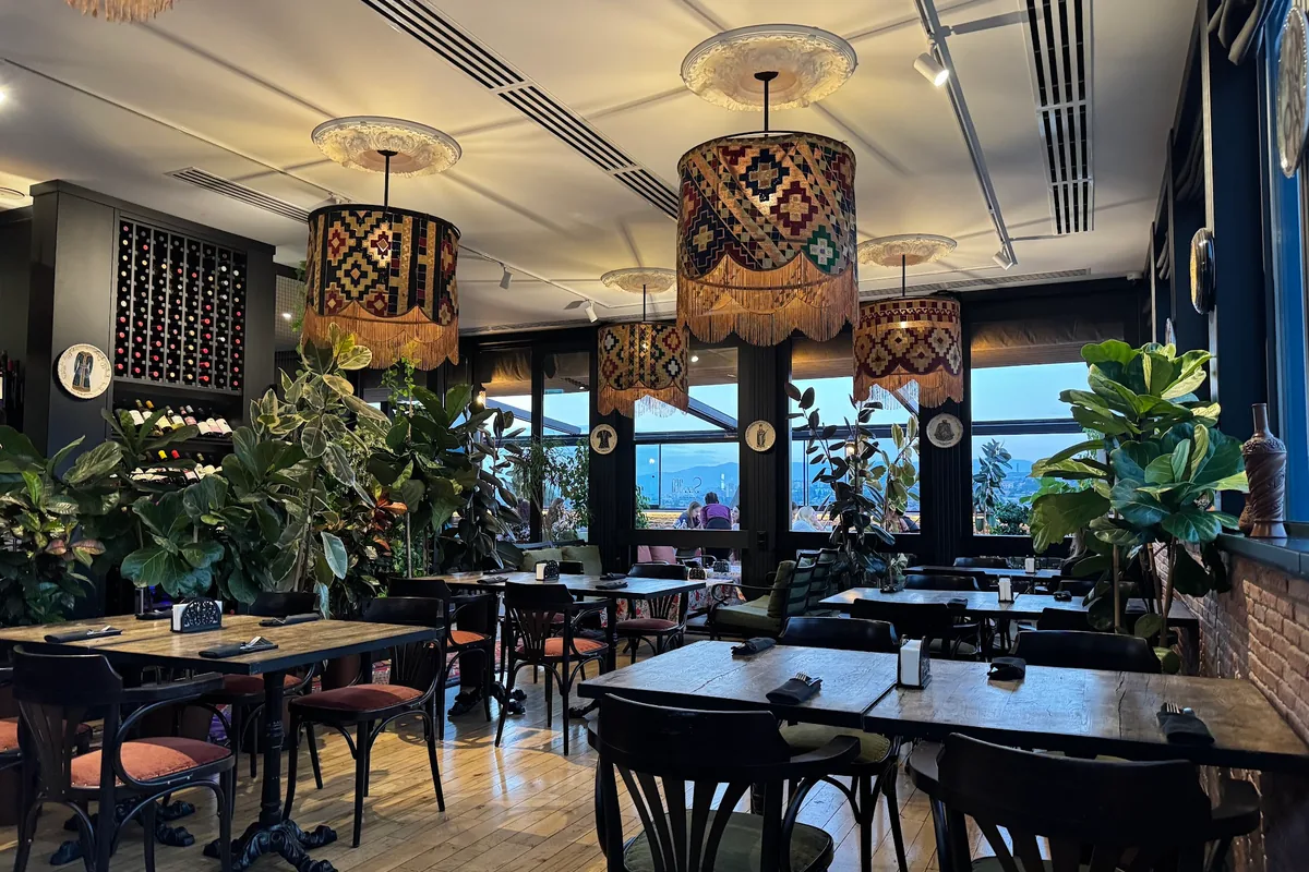 Dining room with patterned pendant lamps and potted plants at See360 Restaurant