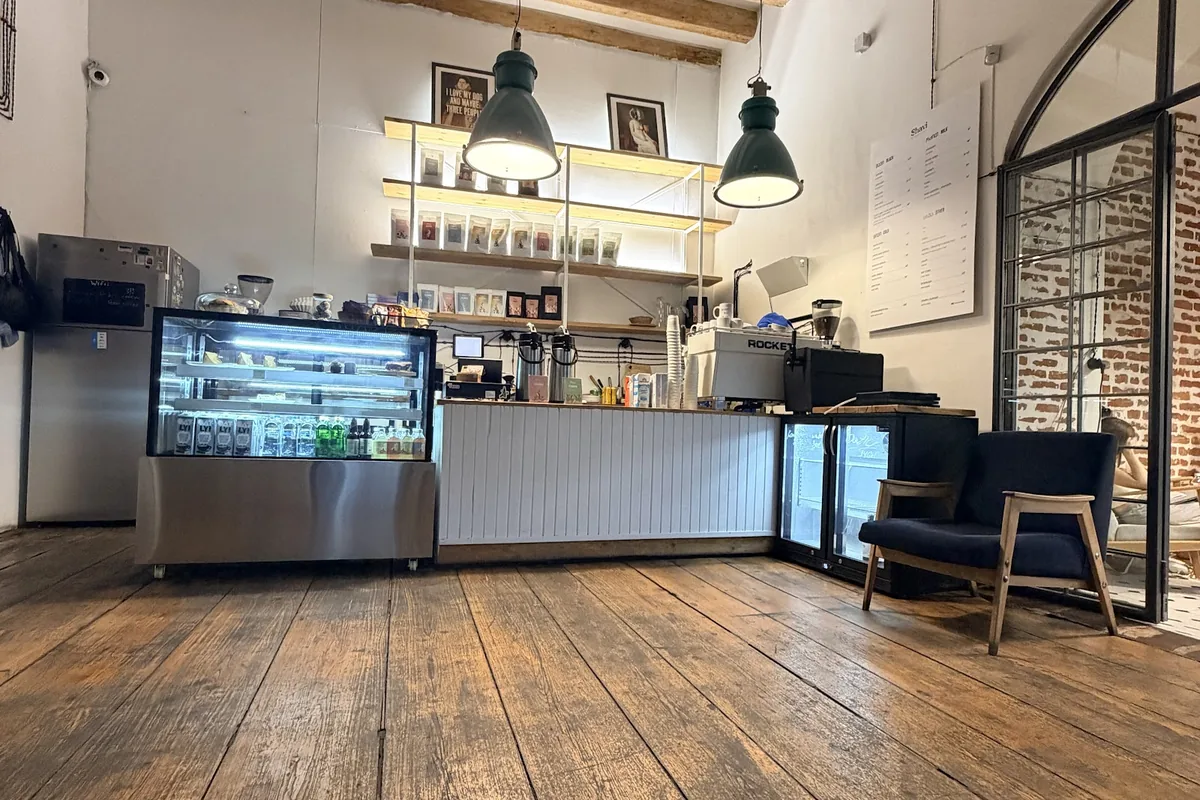 Coffee counter with green pendant lamps and shelves of roasted beans at Shavi Coffee Roasters on Ninoshvili Street