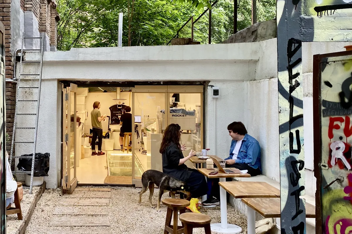 The tree-shaded courtyard with wooden tables in front of the converted garage roastery at Shavi Coffee Roasters in Sololaki
