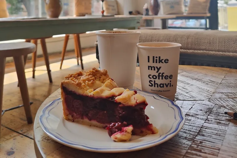 Berry pie slice on a plate with takeaway coffee cups at Shavi Coffee Roasters - The Original
