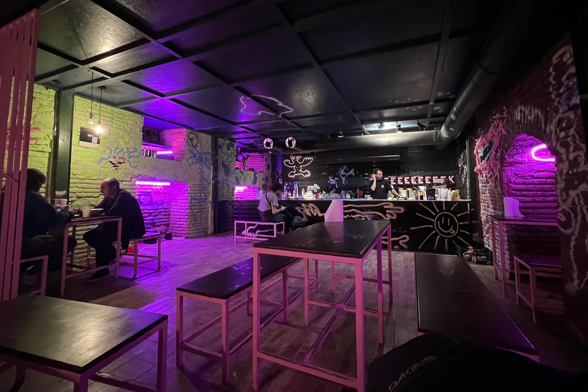 Underground seating with neon lighting and painted brick walls at Shpana