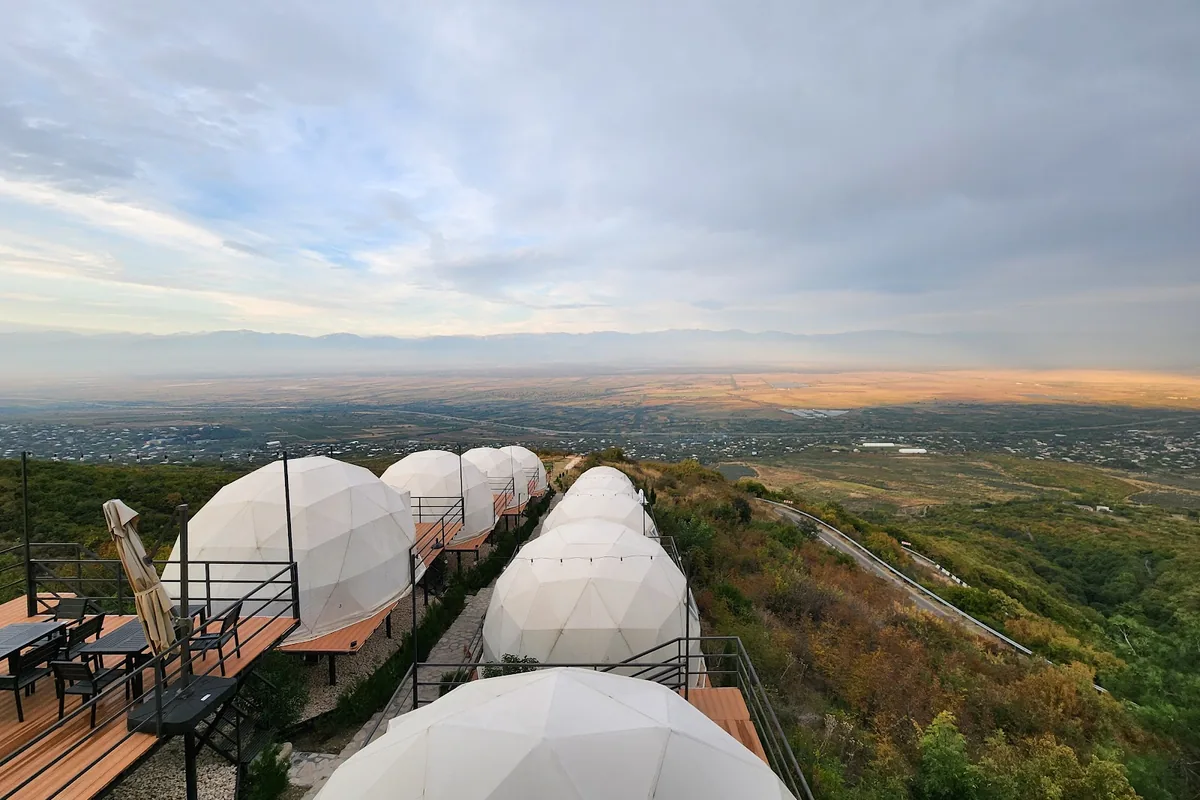 A row of white dome tents on decks along the ridge above the Alazani Valley at Signagi Glamping