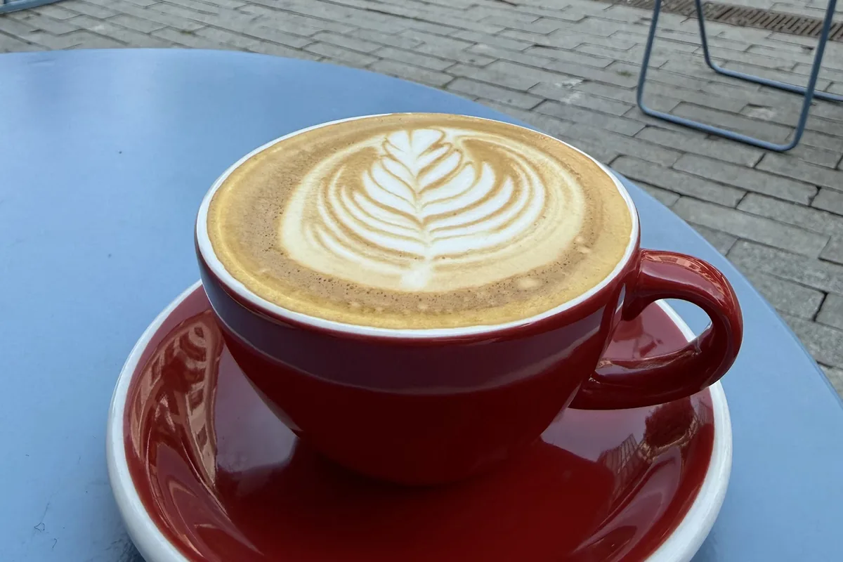 Cappuccino in a red cup on a patio table outside Slow on Aghmashenebeli Avenue
