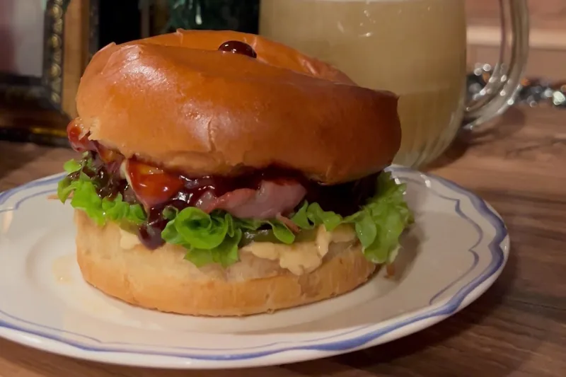 Burger with lettuce and sauce beside a mug of beer at Sma Craft Beer Bar
