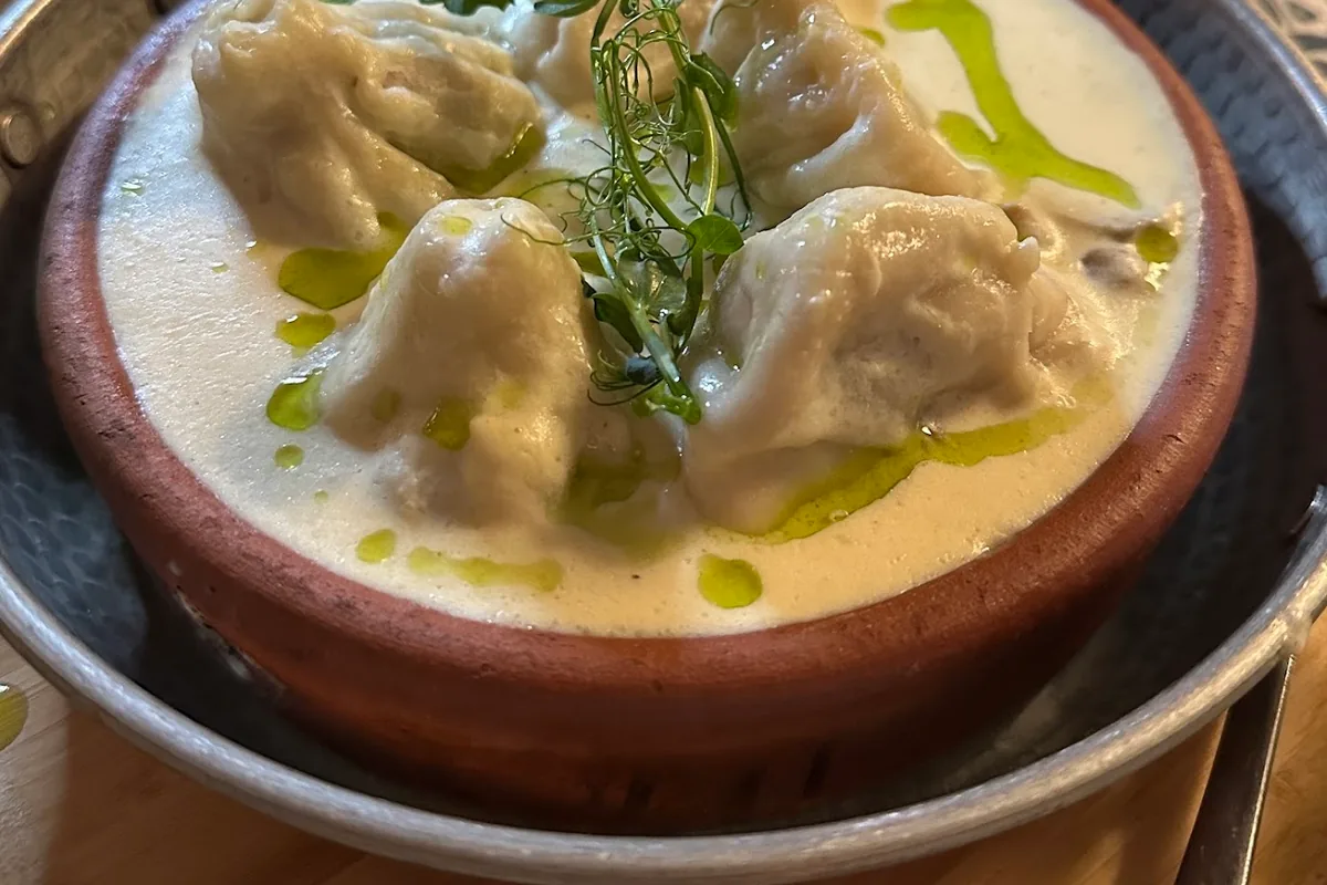 Khinkali in creamy garlic sauce in a clay bowl at Sormoni