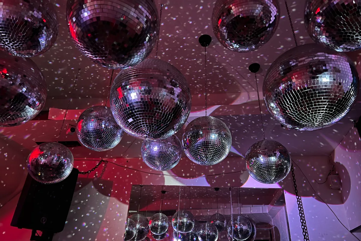 Disco balls hanging from the ceiling with light reflections at Success Bar