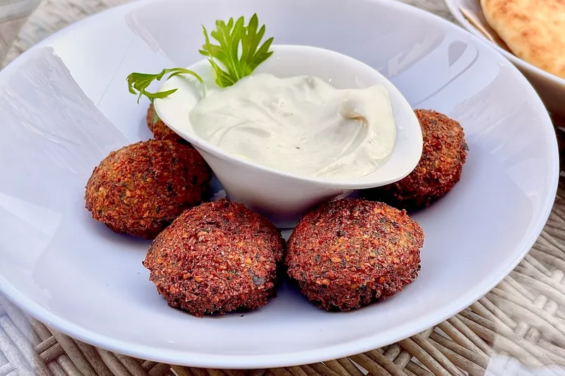 Falafel with white dipping sauce in a bowl at Supra Hummus
