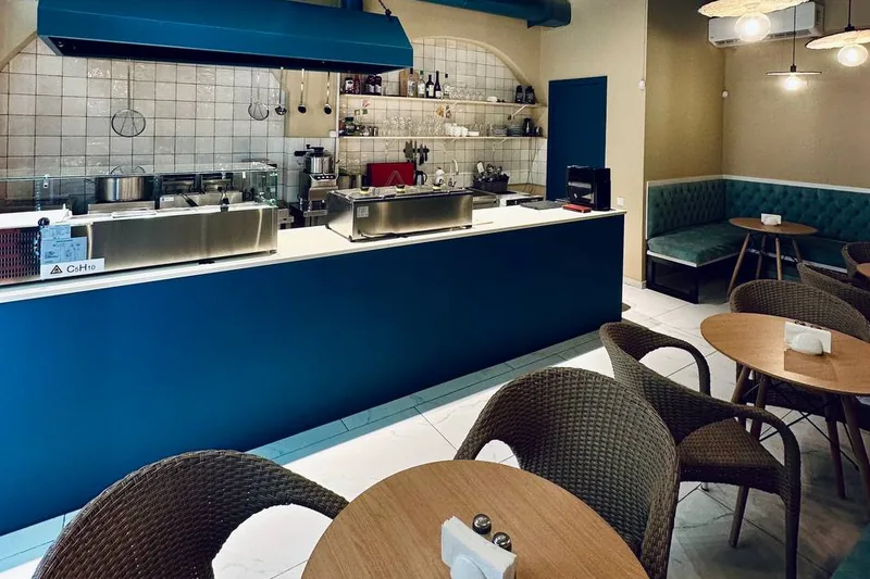 Dining area and service counter with blue ceiling and woven pendant lamps at Supra Hummus
