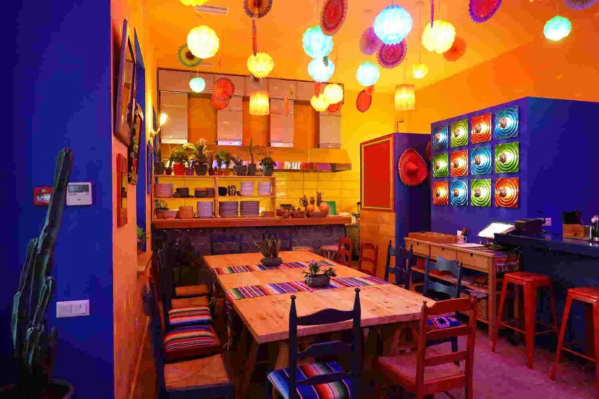 Long wooden table under colorful paper lanterns at Taqueria Teko's Tacos
