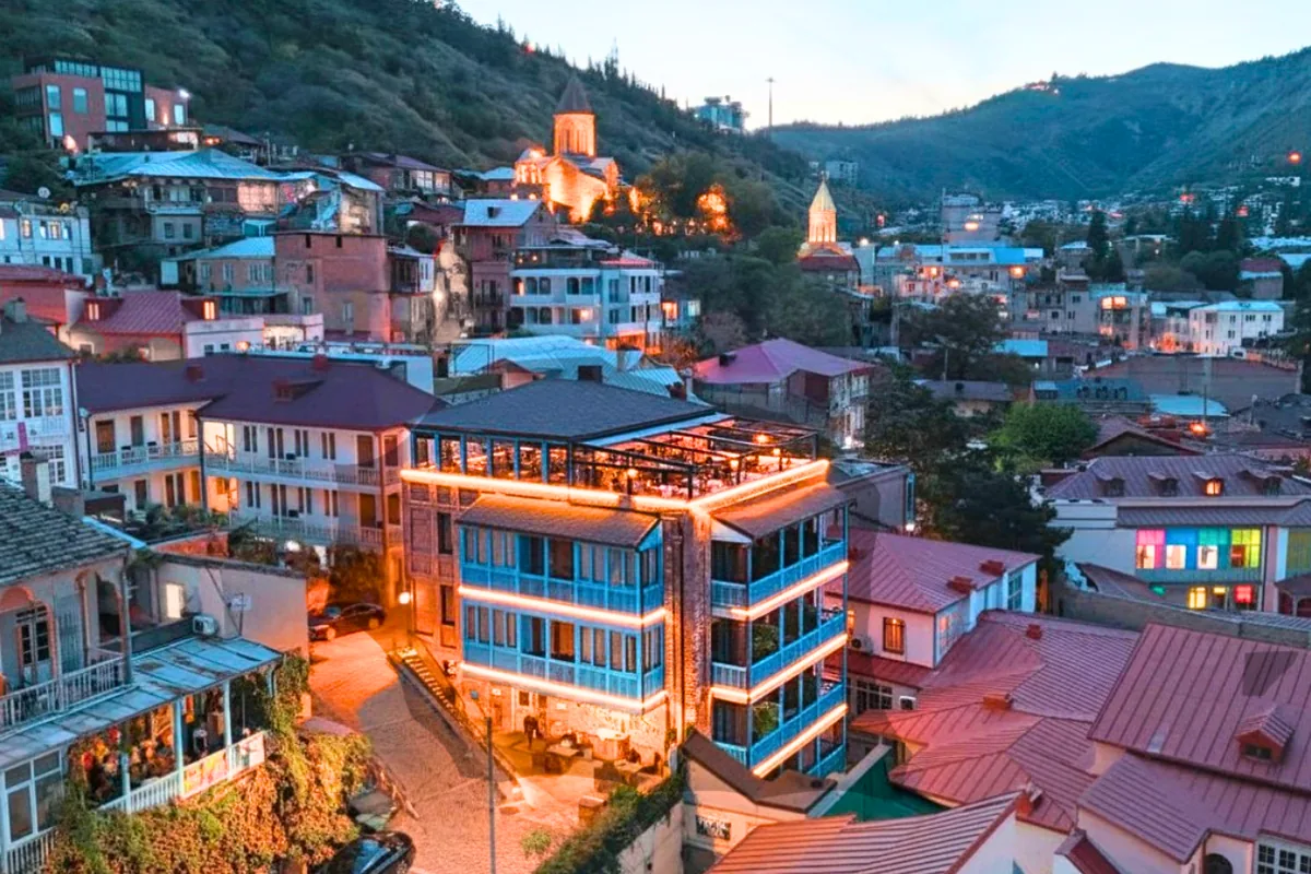 TbiliSee Hotel's blue balconies and lit rooftop bar above the Old Town at dusk