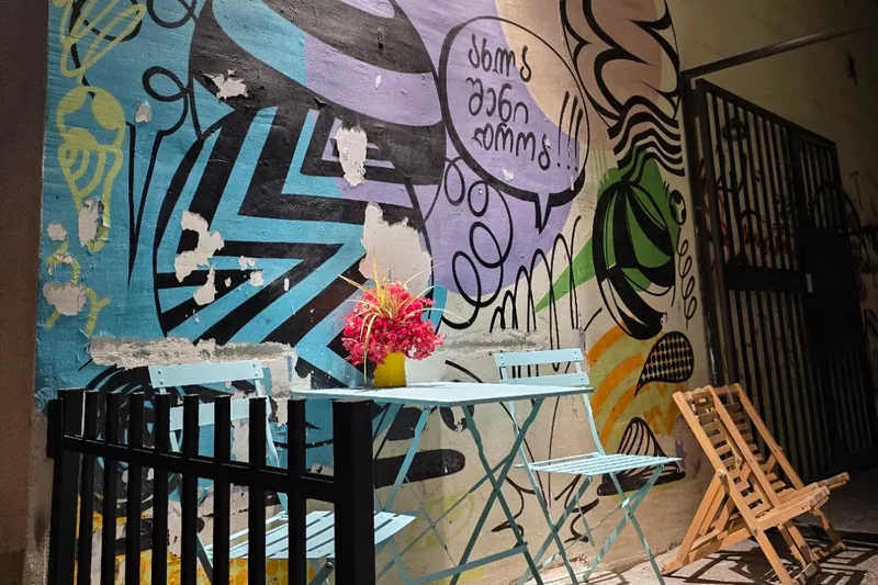 Outdoor patio seating with painted mural wall at The Cone Culture