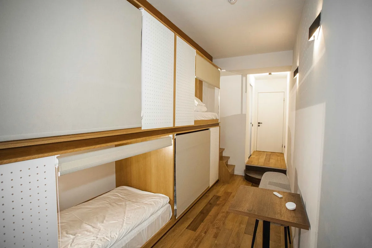 A 4-bed pod room at The Tbilisi Pod, with wooden capsule bunks behind blinds and a small work table