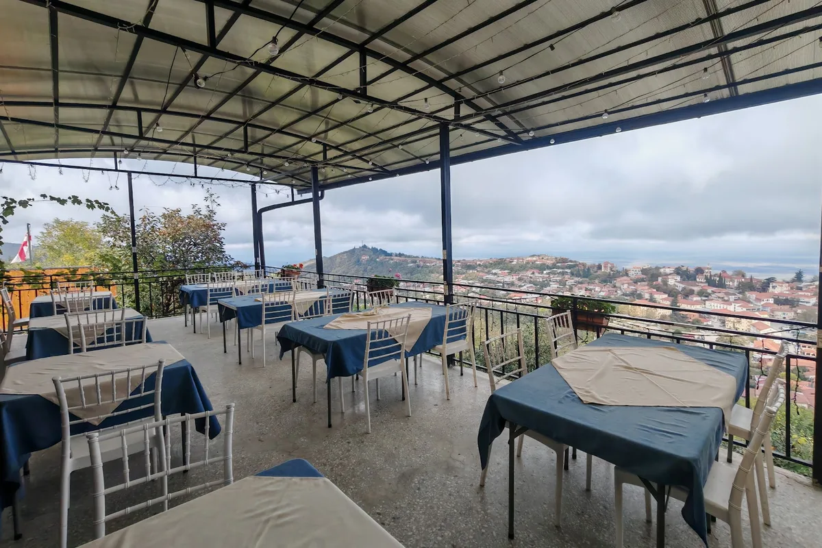 Covered deck with blue-clothed tables looking out over Sighnaghi's roofs at The Terrace