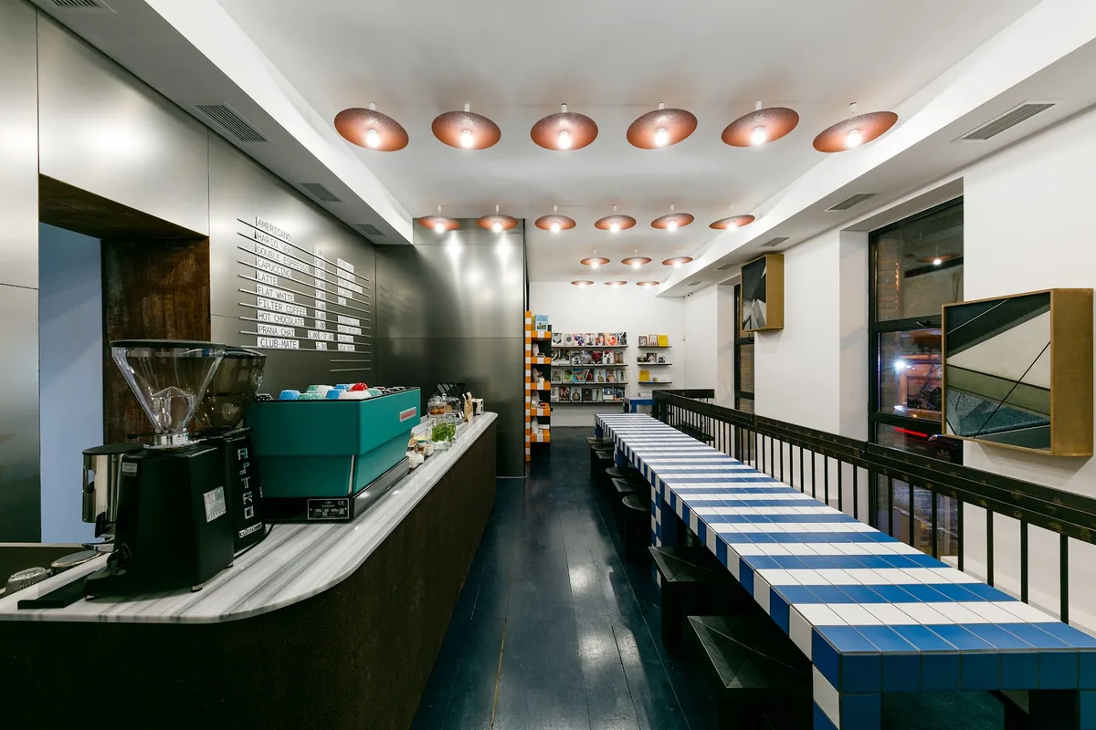 Espresso bar, blue-and-white tiled bench and shelves of books and magazines at They Said Books