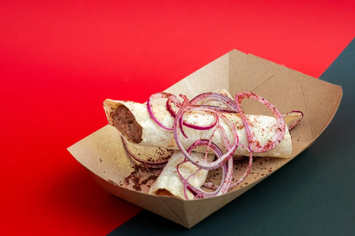 Kebab wraps with red onion in a cardboard tray at Tsetskhli Ainto