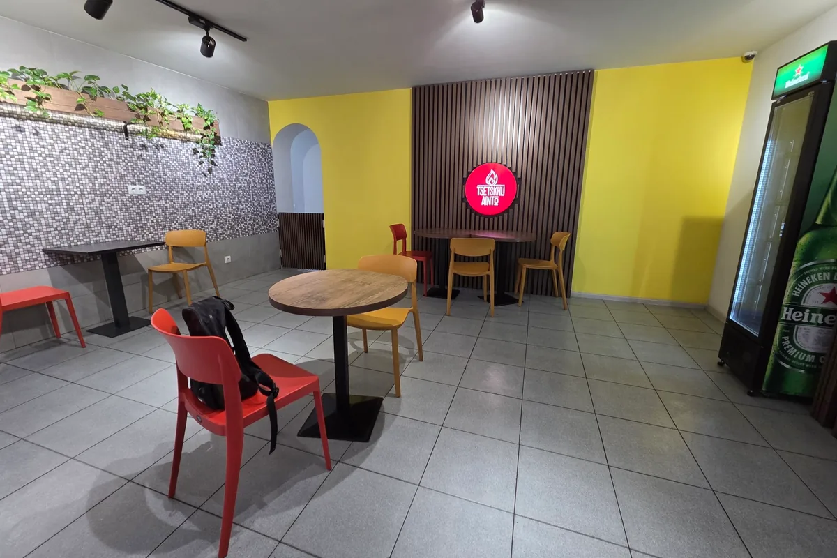Yellow-walled dining room with the red Tsetskhli Ainto sign, Tbilisi