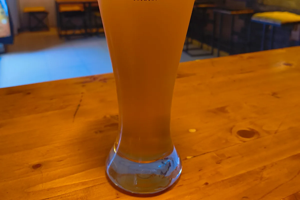 Glass of megobrebi craft beer on a wooden counter at Tsota Tsota
