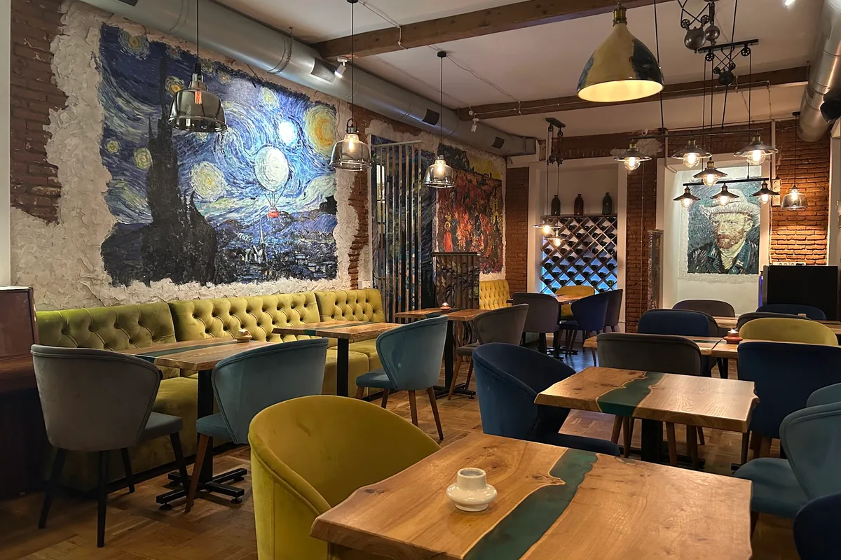 Dining room with starry night mural and wooden tables at Van Goghi