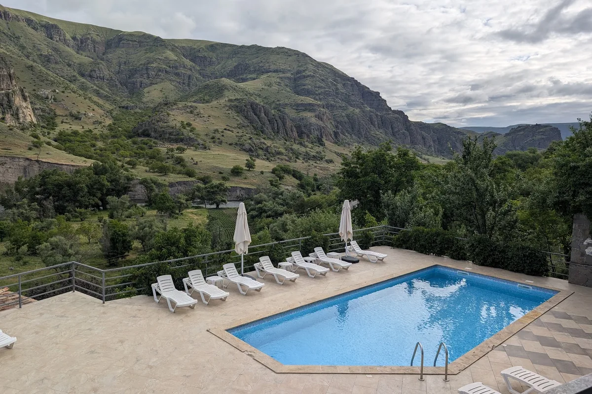 The pool terrace at Vardzia Resort, with sun loungers above the green Mtkvari valley and its cliffs