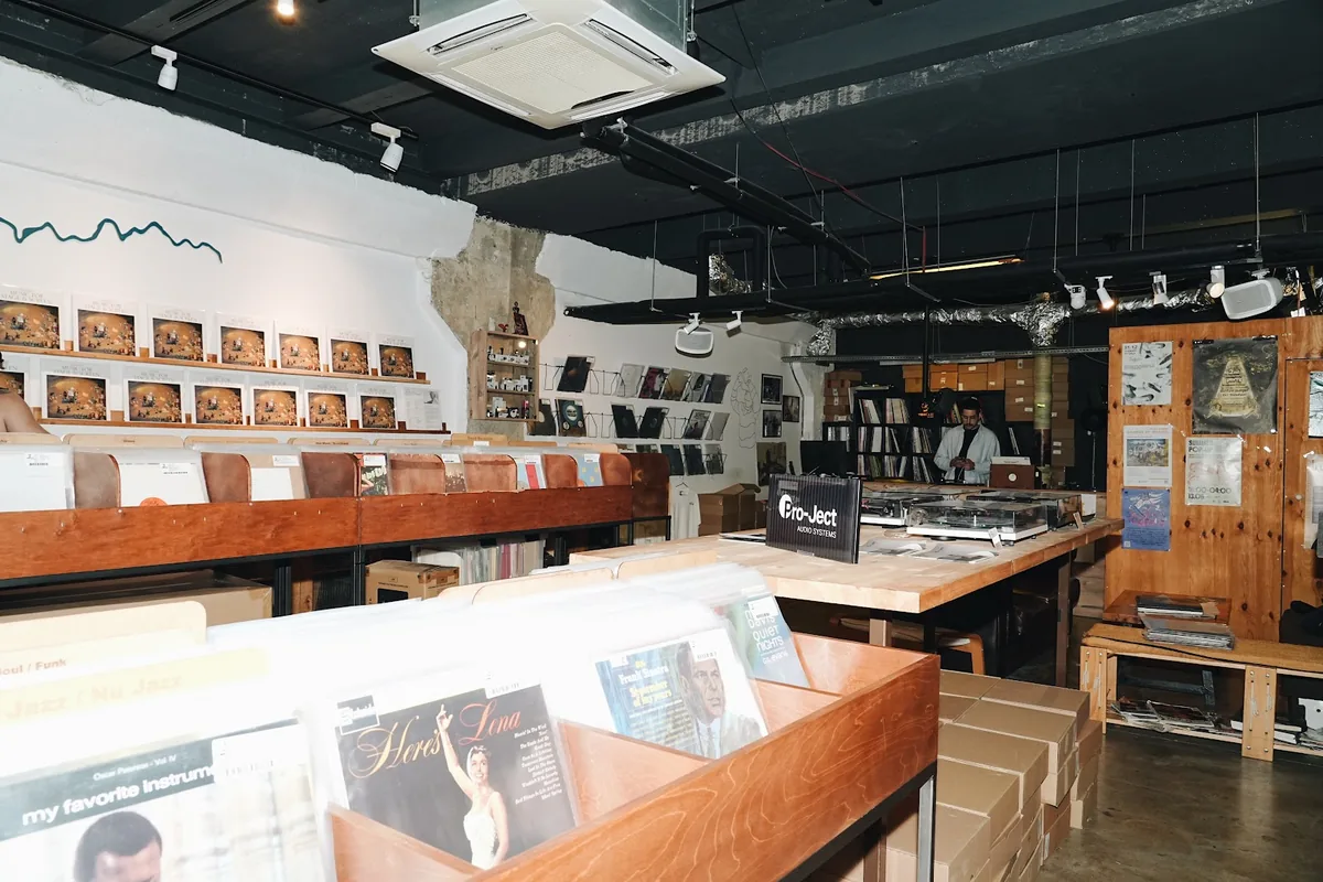 Record bins, wall racks of vinyl and turntables on a wooden counter inside Vodkast Records at Fabrika