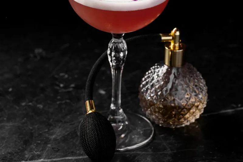 A cocktail in a coupe glass garnished with edible flowers at the Weather Report Sky Bar