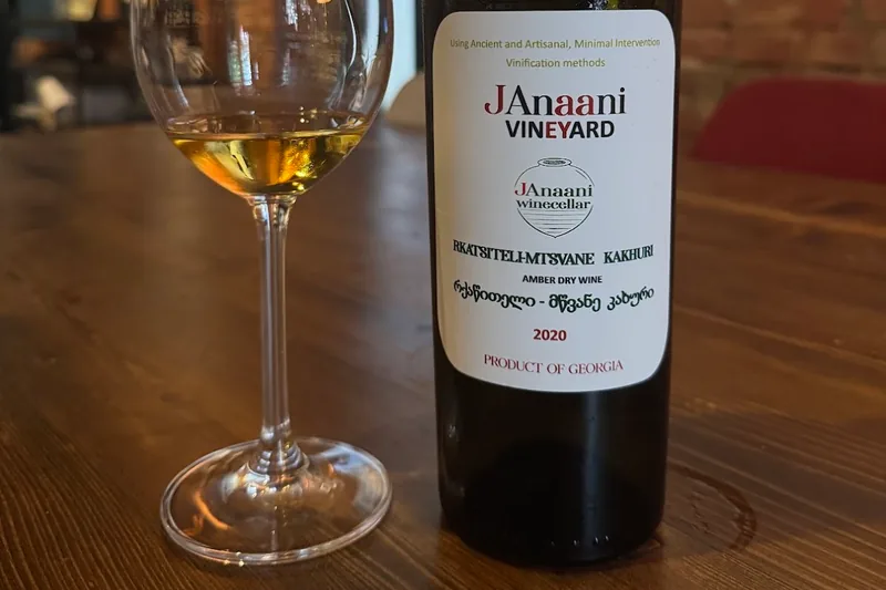 Amber wine in a glass next to a janaani wine bottle at Wine Boutique