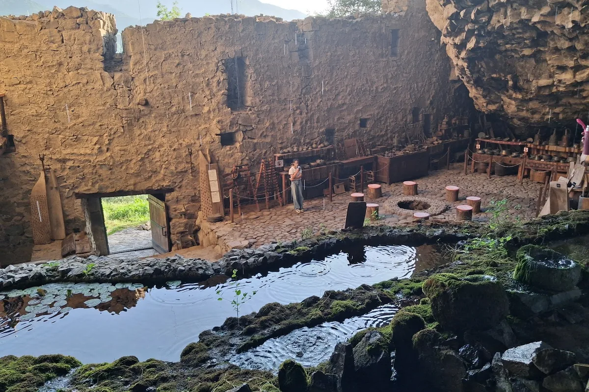 Old stone walls and spring-fed pools inside the cave at Zarni Parni near Haghpat