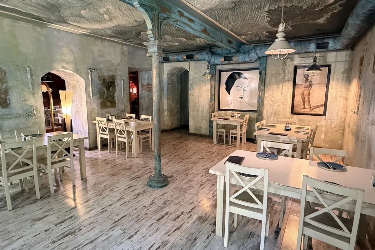 Dining room with white chairs and an old painted ceiling at Zodiaqo