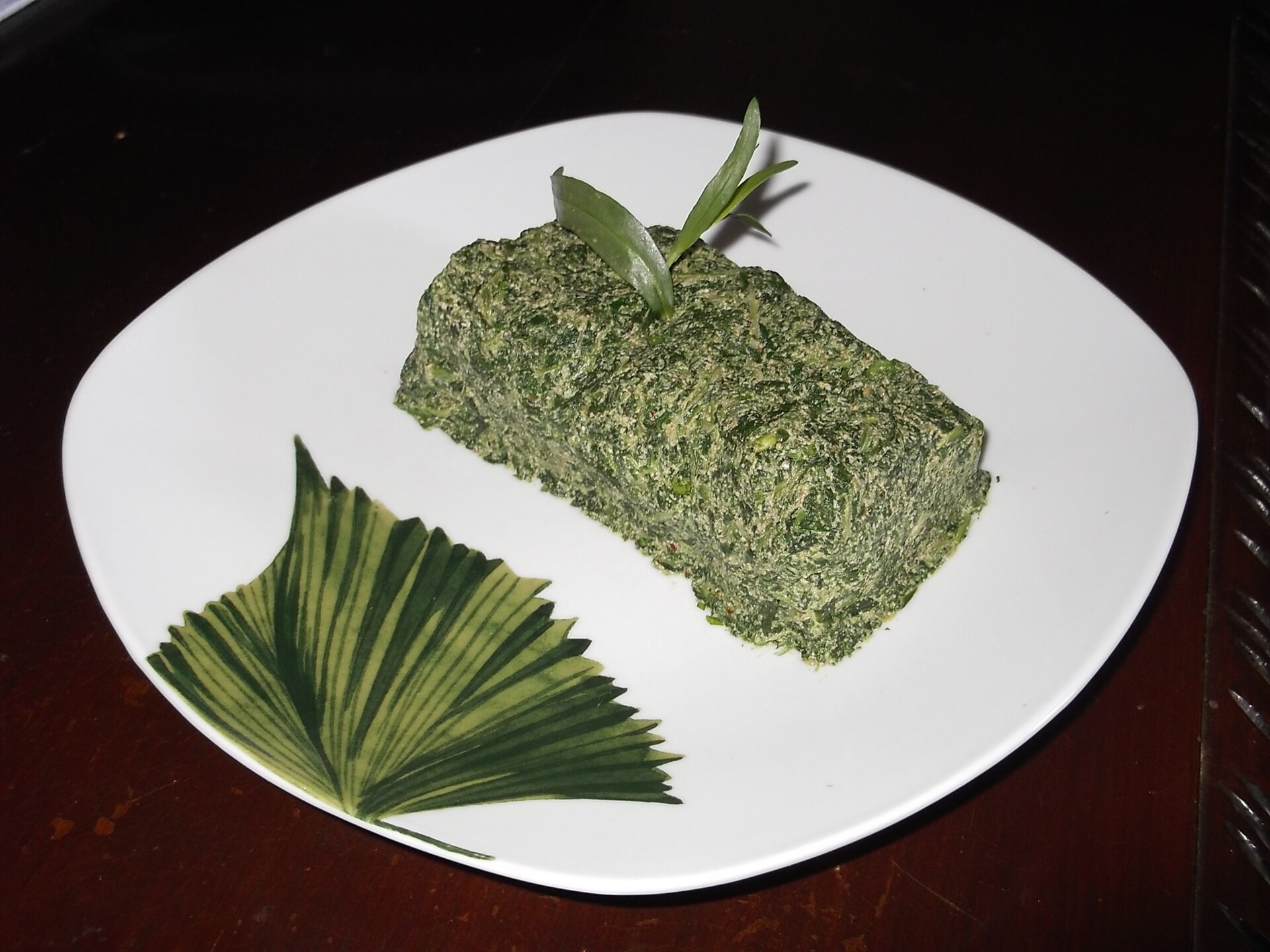A block of spinach pkhali, the Georgian walnut and herb pâté, on a white plate