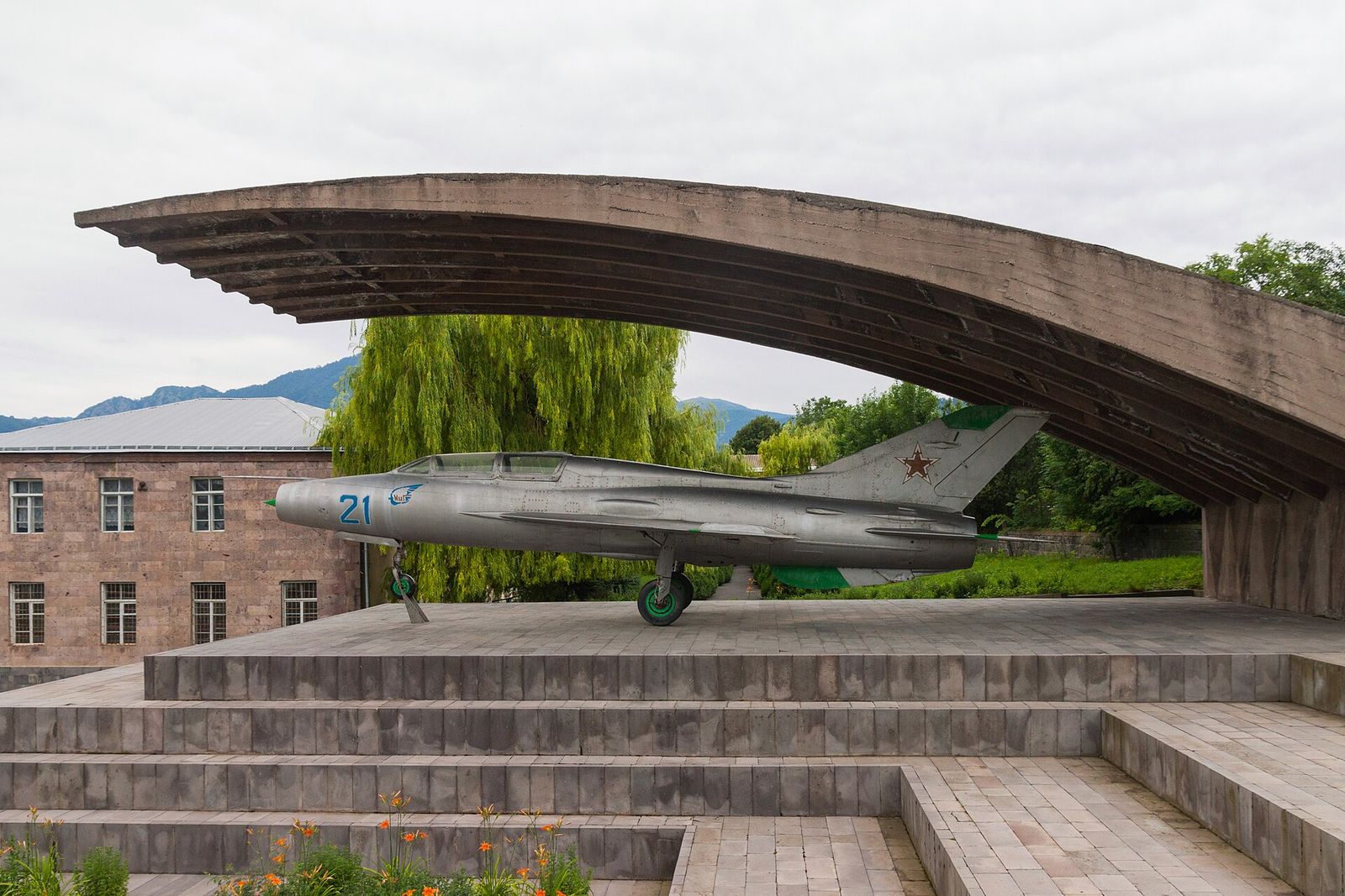 A MiG-21 jet under a curved concrete canopy outside the Mikoyan Brothers Museum in Sanahin, Armenia