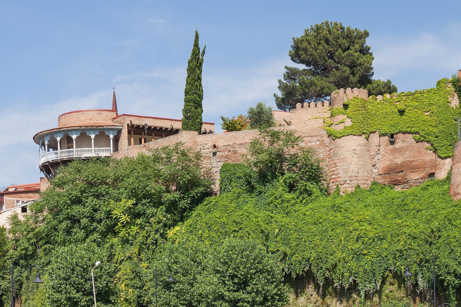 The round wooden balcony of Queen Darejan's Palace on top of old brick walls covered in ivy, Avlabari