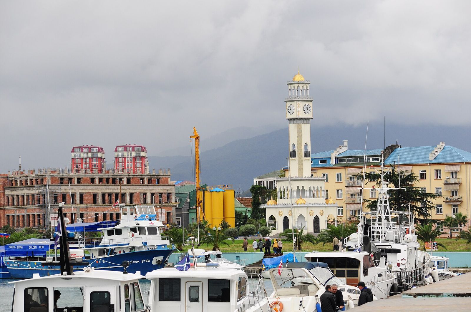 The white Chacha Tower with its clock faces and gold dome behind the boats moored in Batumi's marina