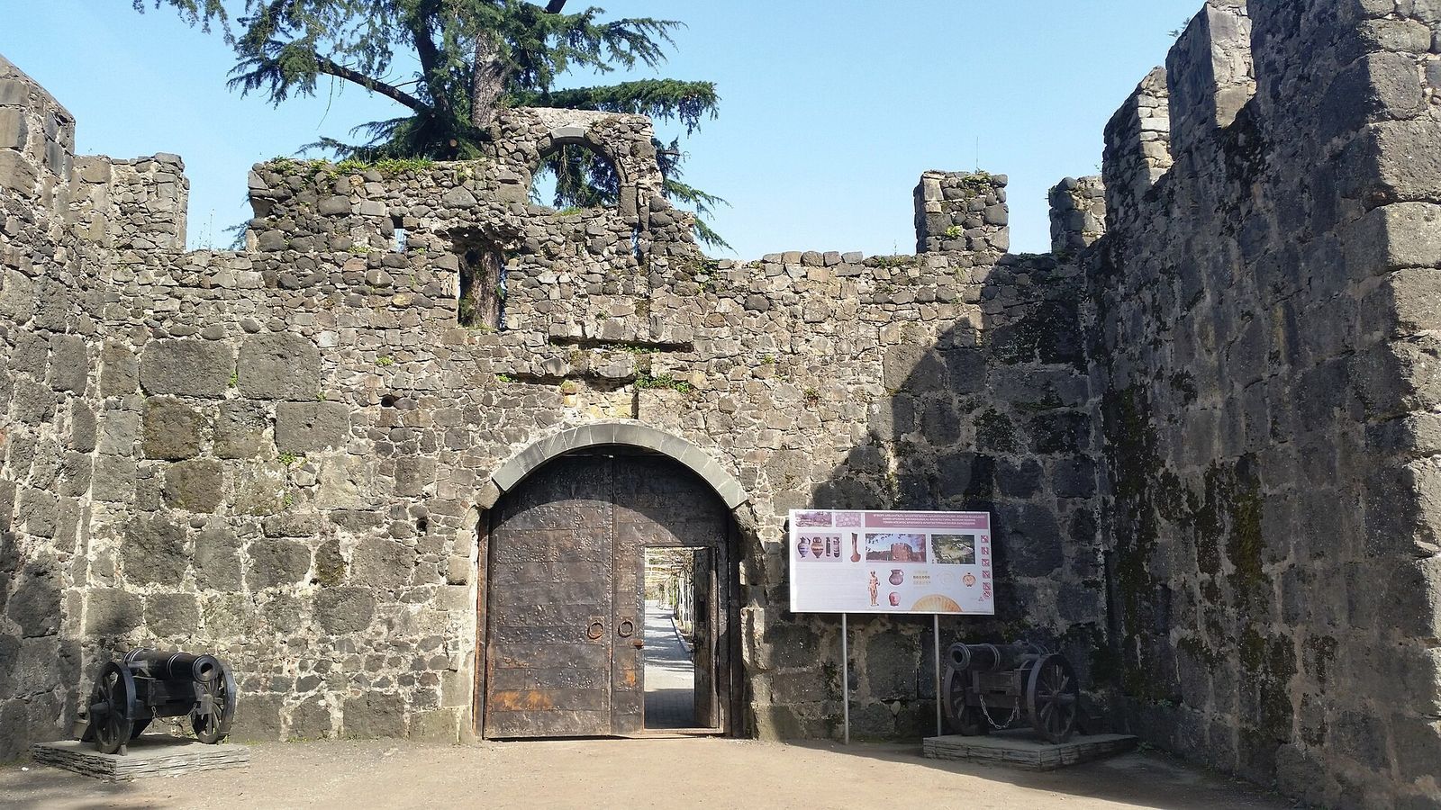 The arched wooden gate in the crenellated stone walls of Gonio-Apsaros Fortress